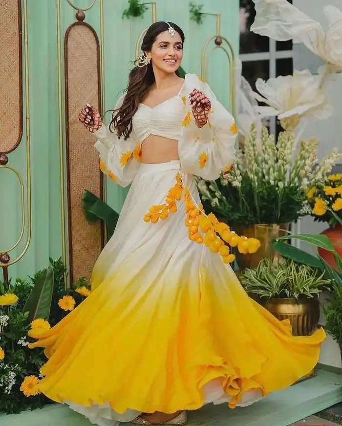 हल्दी समारोह भारतीय विवाह समारोहों में एक महत्वपूर्ण स्थान रखता है, जिसे पारंपरिक रूप से जीवंत पीले रंगों की उपस्थिति से चिह्नित किया जाता है। हाल ही के रुझानों में पारंपरिक पीले परिधानों से विचलन देखा गया है, लोग इस विशेष अवसर के लिए रंगों और थीमों की एक विविध सीरीज का चयन कर रहे हैं। आइए जानते है इसके बारे में